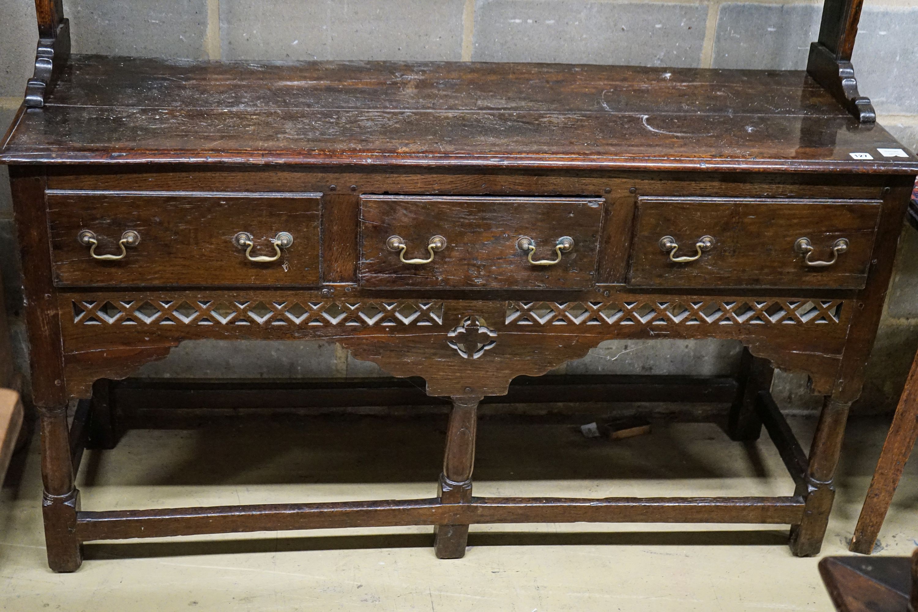 A mid 18th century oak dresser, with pierced cornice and three shelf rack over three drawers, with pierced frieze and turned and squared underframe, width 142cm, depth 46cm, height 204cm